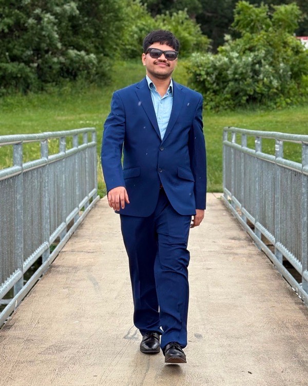 Jaya Prakash Yadav Gorla in a navy suit, walking across a footbridge